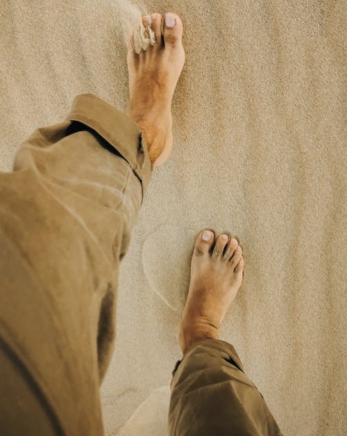 barefoot person walking on a sandy beach